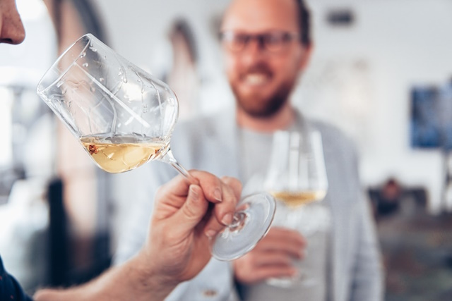 Person evaluating a glass of white wine with viscous legs